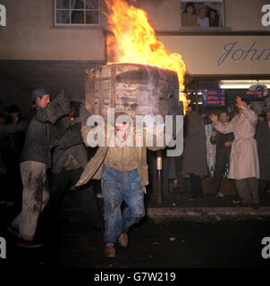 Tar Barrel Burning Ceremony - Ottery St Mary's. Ein Mann trägt ein brennendes Fass auf seinen Schultern, während die Menschen darauf schauen. Stockfoto