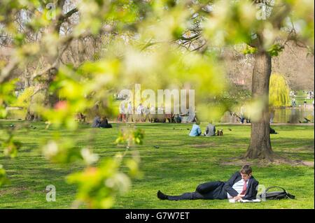 Ein Mann liegt im St James Park, London, in der Sonne, während das warme Wetter in einem großen Teil des Vereinigten Königreichs andauert. Stockfoto