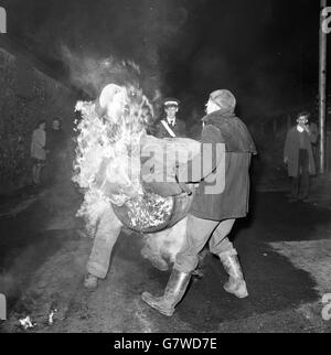 Tar Barrel Burning Ceremony - Ottery St Mary's. Die Schlacht beginnt, als ein Mann versucht, die flammende Last von einem anderen zu fangen. Stockfoto
