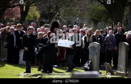 Mitglieder der Öffentlichkeit beobachten, wie der Sarg eines nicht identifizierten Jungen nach einer Trauerfeier auf dem Seafield Cemetery in Edinburgh zu seiner Grabseite getragen wird, fast zwei Jahre nachdem er tot auf einem Pfad gefunden wurde. Stockfoto