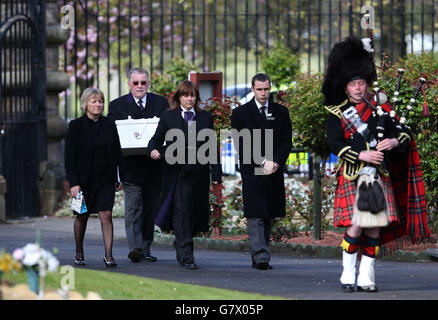 Ministerin Erica Wishart (links) aus der Tranent-Pfarrkirche, als der Sarg zur Grabseite für die Beerdigung eines nicht identifizierten Jungen auf dem Seafield Cemetery in Edinburgh geleitet wird, fast zwei Jahre nachdem er tot auf einem Pfad gefunden wurde. Stockfoto