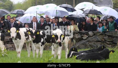 Der Bauer Cathal Garvey steht neben Taoiseach Enda Kenny, und Li Keqiang, Premierminister der Volksrepublik China, und seine Frau Professor Hong Cheng (rechts) winken unter Regenschirmen während eines Besuchs auf Garveys Farm in Gortbrack ower, County Mayo, während der chinesische Premierminister zwei Tage in Irland verbringt. Stockfoto