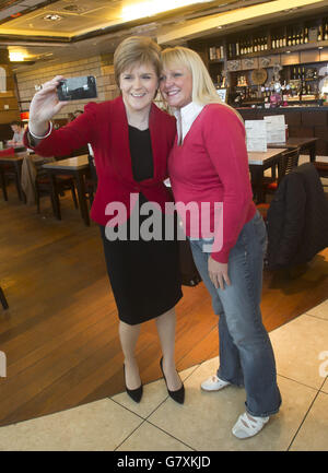 SNP-Leiterin Nicola Sturgeon (links) hält für ein Selfie mit einem Mitglied der Öffentlichkeit, als sie am Flughafen Edinburgh ankommt, bevor sie nach London fliegt. Stockfoto