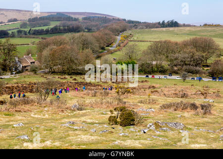 Eine Gruppe von jungen Schulkinder mit Klettern hüten aufsteigend bis Hound Tor auf Dartmoor, Devon, England, UK Stockfoto