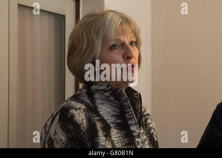 Innenministerin Theresa May spricht mit den Beamten der Einwanderungsbehörde, nachdem die Beamten Wohnimmobilien auf der Suche nach illegalen Einwanderern in Southall, West London, überfallen hatten. Stockfoto