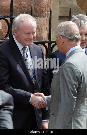 Der Prinz von Wales schüttelt sich die Hände mit dem stellvertretenden Premierminister von Nordirland, Martin McGuinness (links), während der erste Minister, Peter Robinson, vor der St. Patrick's Church in Belfast schaut. Stockfoto
