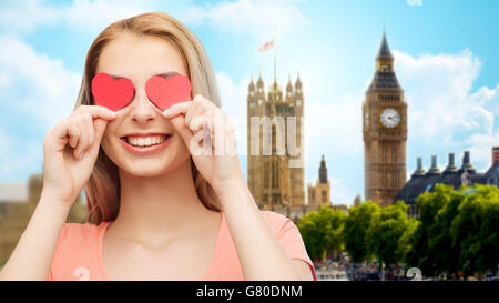 glückliche junge Frau mit roten Herzformen auf Augen Stockfoto