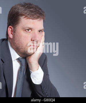 Business-Mann besorgt Finanzplan auf grauem Hintergrund isoliert Stockfoto