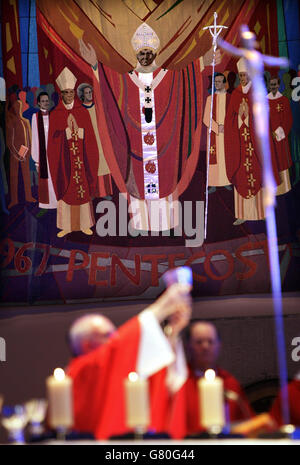 Ein Wandteppich, auf dem der verstorbene Papst Johannes Paul II. Abgebildet ist, blickt herab, während Erzbischof Patrick Kelly die Messe feiert. Stockfoto