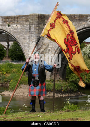 Das Mitglied der Wallace Society Eddie McNeill aus Strachur schwingt eine wehende Löwenfahne von der Stirling Bridge als Denkmal an der Stelle der "Braveheart Schlacht", wo William Wallace und Andrew de Moray Schottland zum Sieg bei der Schlacht von Stirling Bridge im Jahr 1297 führten. Stockfoto