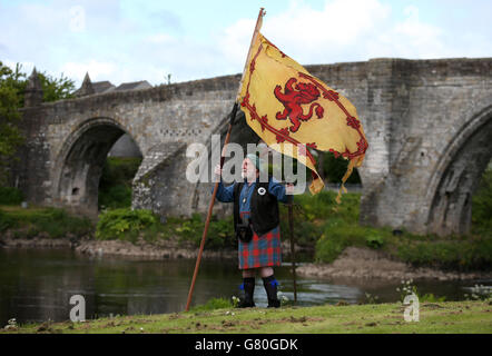 Das Mitglied der Wallace Society Eddie McNeill aus Strachur schwingt eine wehende Löwenfahne von der Stirling Bridge als Denkmal an der Stelle der "Braveheart Schlacht", wo William Wallace und Andrew de Moray Schottland zum Sieg bei der Schlacht von Stirling Bridge im Jahr 1297 führten. Stockfoto