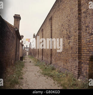 Grimmige Gefängnismauer auf der einen Seite mit den kleinen Häusern der Gefängnisbeamten auf der anderen Seite. Die hohe Mauer ist die, über der Gefangene entkommen sind. Wandsworth Prison, South West London, erbaut 1851. Stockfoto