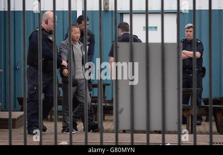 Ein Mann wird vom Personal der Grenztruppen im Harwich International Port in Essex weggeführt, da 68 Personen beurteilt wurden, wobei sieben ins Krankenhaus gebracht wurden, nachdem Berichte über Menschen, die in einem Container im Harwich International Port, East of England Ambulance Service, eingeschlossen wurden. Stockfoto