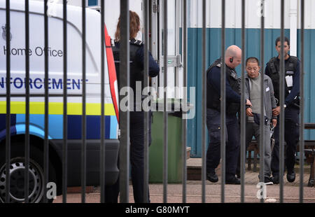 Ein Mann wird vom Personal der Grenztruppen im Harwich International Port in Essex weggeführt, da 68 Personen beurteilt wurden, wobei sieben ins Krankenhaus gebracht wurden, nachdem Berichte über Menschen, die in einem Container im Harwich International Port, East of England Ambulance Service, eingeschlossen wurden. Stockfoto