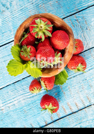 Frischen Erdbeeren Haufen in Schüssel mit Blättern auf alten Holzdielen gelegt. Schuss aus Vogelperspektive Stockfoto