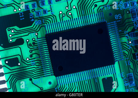 Technologiekonzept. Leiterplatte/leiterplatte mit blau und grün leuchtenden Komponenten. Verdrahtung im Computer, Stromkreistaufschluss, Elektronik Stockfoto