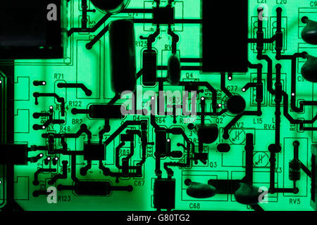 Computertechnik Konzept. Leiterplatte / leiterplatte mit Komponenten, die mit grüner Beleuchtung hinterleuchtet sind. Verdrahtung im Computer, Stromkreistaufschluss, Elektronik. Stockfoto