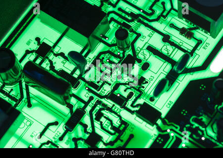 Computertechnik Konzept. Leiterplatte / leiterplatte mit Komponenten, die mit grüner Beleuchtung hinterleuchtet sind. Verdrahtung im Computer, Stromkreistaufschluss, Elektronik. Stockfoto
