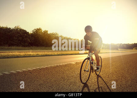 Einzigen männlichen Radfahrer in Shorts, Helm und Sonnenbrille training für Long Distance Rennen auf Rennrad bei Sonnenaufgang mit Kopie Stockfoto