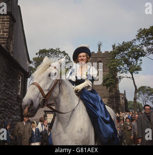 Beim Girlande Day „King“ wird seine Blumengirlande entfernt, während die „Queen“ zuschaut. Die Girlande wird dann auf die Kirchturmspitze gehisst. Peveril Castle ist im Hintergrund. Stockfoto