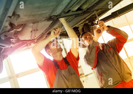 Kfz-Mechaniker, die Festsetzung von Auto in der Garage - Teamarbeit Stockfoto