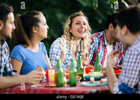 Freunden im Freien zu essen und Spaß haben nach dem Grillen Stockfoto