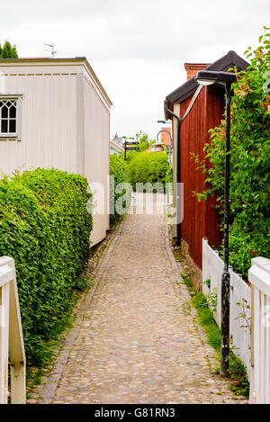 Söderköping, Schweden - 20. Juni 2016: Schmale Gasse mit kleinen Gebäuden auf beiden Seiten. Stein Felsbrocken ebnen den Weg. Stockfoto