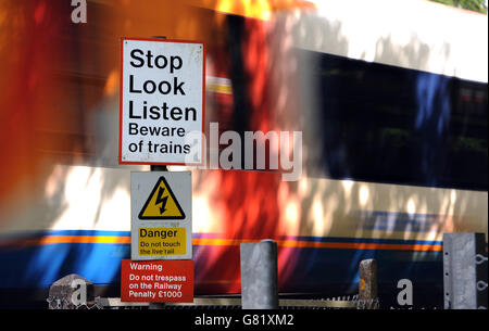 Ein Zug fährt an einem Stop, Look, Listen-Schild vorbei, das Mitglieder der Öffentlichkeit vor entgegenkommenden Zügen am Fußgängerübergang in der Nähe von Worting Junction in Hampshire warnt Stockfoto