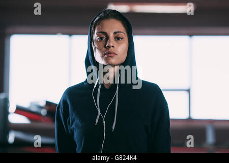 Porträt von müde Frau tragen Kapuzen Shirt stehen im Fitnessraum Stockfoto