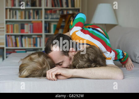 Glücklicher Vater liegend mit fröhlichen Kindern im Bett zu Hause Stockfoto