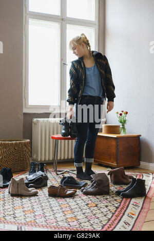 Junge Frau Wahl Schuhe stehen im Wohnzimmer zu Hause Stockfoto