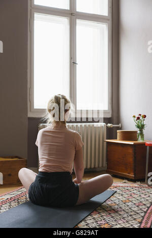 Rückansicht der Frau beim Yoga im Wohnzimmer Stockfoto