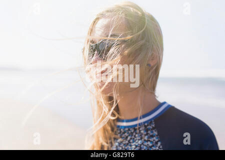 Glückliche junge Frau mit windigen Haar am Strand Stockfoto