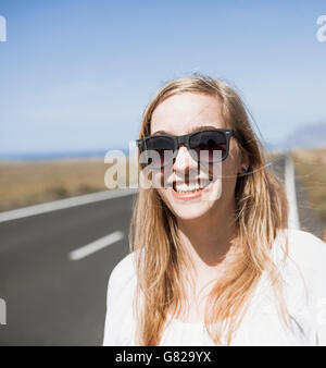 Lächelnde junge Frau mit Sonnenbrille unterwegs Stockfoto