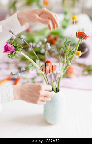 Bild der Frau, die Vermittlung von Blumen in Vase auf den Tisch zu Hause abgeschnitten Stockfoto