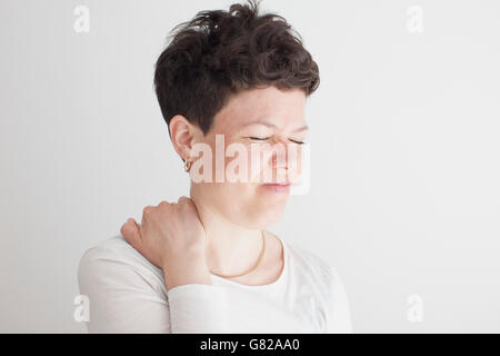 Nahaufnahme der Mitte erwachsenen Frau leidet Schmerzen in der Schulter vor weißem Hintergrund Stockfoto