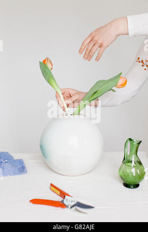 Zugeschnittenes Bild Mitte erwachsenen Frau arrangieren Blumen in Vase auf Tisch Stockfoto