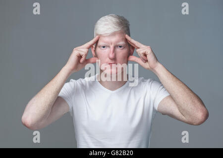 Porträt des jungen Mann mit Kopf in Händen vor grauem Hintergrund Stockfoto