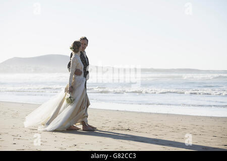Gesamte Länge der liebende Braut und Bräutigam zu Fuß am Strand Stockfoto