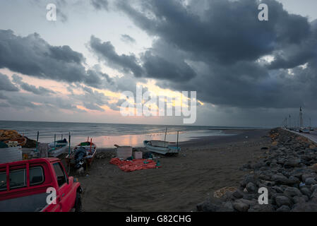 Angeln Boote und eine Abholung an einem Strand bei Sonnenaufgang gegen ein bewölkter Himmel brechen in goldenen Farben wie die Sonne aufgeht Stockfoto