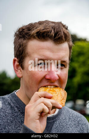 Ein junger Mann Essen eine Torte in der jährlichen Dorffest In Nutley, East Sussex, Großbritannien Stockfoto