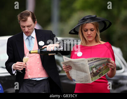 Ein Rennegoist prüft die Rennkarten und formt sich in der Zeitung Racing Post aus, als ein weiterer Champagner am zweiten Tag des Royal Ascot Meeting 2015 auf der Ascot Racecourse, Berkshire, trinkt. Stockfoto