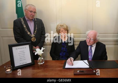 Dublin Oberbürgermeister Christy Burke (links) beobachtet, wie Präsident Michael D. Higgins und seine Frau Sabina im Mansion House in Dublin ein Kondolenzbuch für die Toten beim Berkeley-Balkoneinsturz unterschreiben. Stockfoto