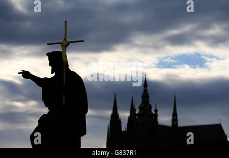 Gebäude und Denkmäler - Blick auf die Stadt Prag. Eine Silhouette einer Statue auf der Karlsbrücke mit der Prager Burg im Hintergrund, Prag. Stockfoto