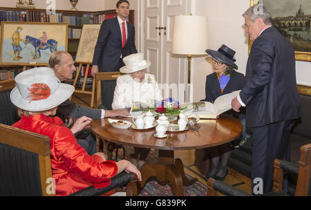 Königin Elizabeth II. Und der Herzog von Edinburgh sitzen am ersten vollen Tag eines Staatsbesuchs in Deutschland mit Bundespräsident Joachim Gauck (rechts), seiner Partnerin Daniela Schadt (im Vordergrund) und einem Dolmetscher (rechts 2) in der offiziellen Berliner Residenz des Präsidenten, dem Schloss Bellevue. Ein Geschenk eines stilisierten Gemäldes der Königin, die auf einem Pony saß, veranlasste den Monarchen zu erklären, dass „das eine lustige Farbe für ein Pferd ist“, als der deutsche Präsident ihr das Kunstwerk überreichte. Stockfoto