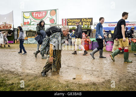 Ein Festivalbesucher rutscht bei einer Regendusche beim Glastonbury Festival auf der Worthy Farm in Somerset in den Schlamm. DRÜCKEN Sie VERBANDSFOTO. Bilddatum: Freitag, 26. Juni 2015. Bildnachweis sollte lauten: Ben Birchall / PA Wire Stockfoto