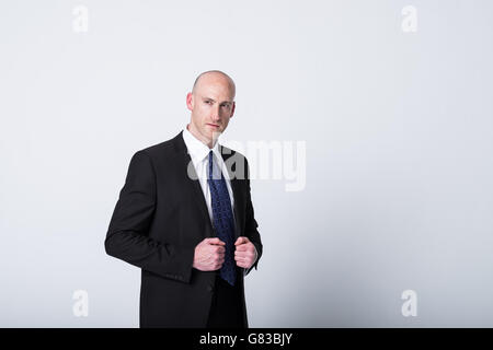 Ein kahler Geschäftsmann in seinen 30ern in einem dunklen Anzug, der zielstrebig und selbstbewusst aussieht Stockfoto