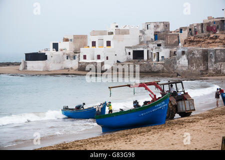 Ein Traktor hilft Fischerboote an Land in Tifnit Strand in der Nähe von Agadir, Marokko zu heben. Stockfoto