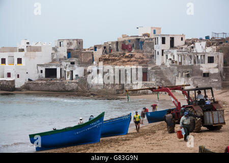 Ein Traktor hilft Fischerboote an Land in Tifnit Strand in der Nähe von Agadir, Marokko zu heben. Stockfoto