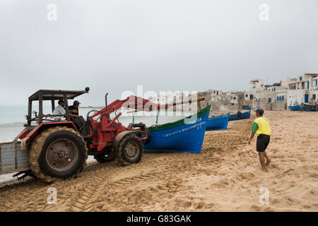 Ein Traktor hilft Fischerboote an Land in Tifnit Strand in der Nähe von Agadir, Marokko zu heben. Stockfoto